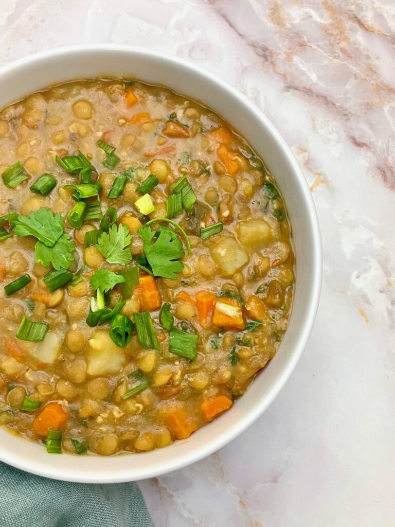 colombian style lentils in a white bowl topped with cilantro and green onion.