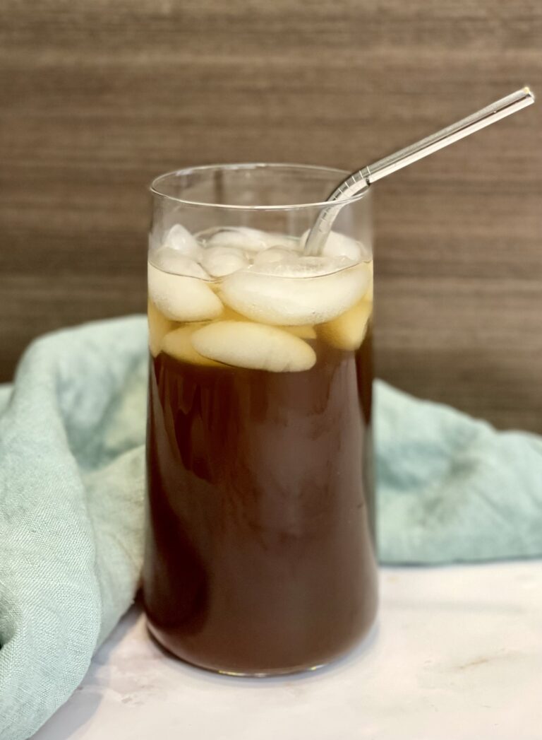 aguapanela served on a clear glass with ice and a metal straw