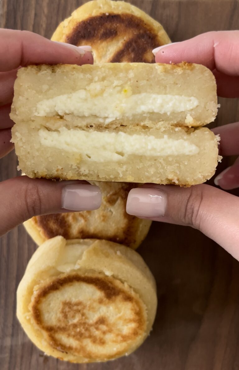 arepa boyacense is split open to reveal the cheesy interior.